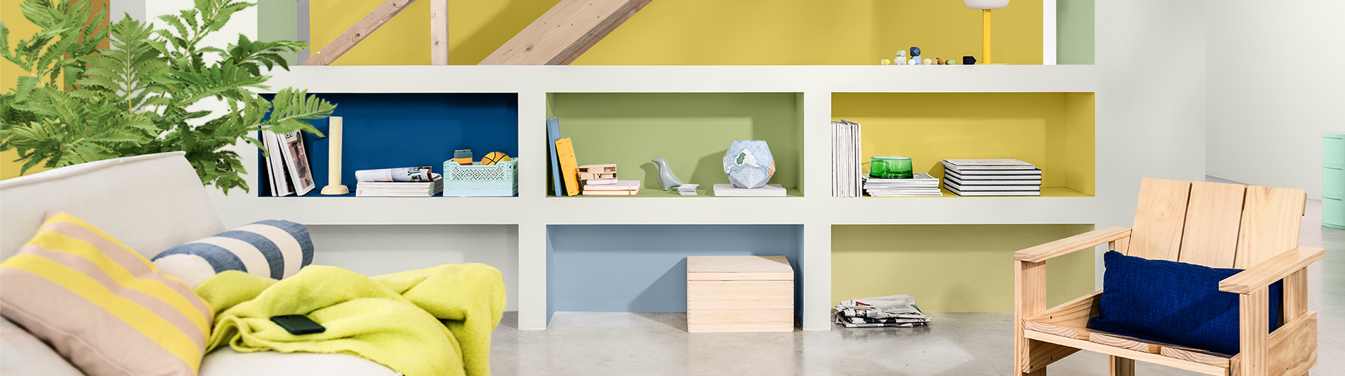 Living room with yellow walls and white and multicoloured shelving unit 