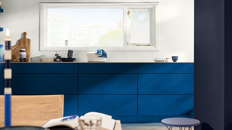 Blue-painted kitchen units against a white wall