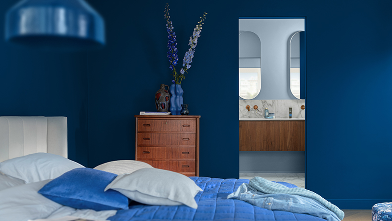 Bedroom with blue walls and a view through to ensuite bathroom 